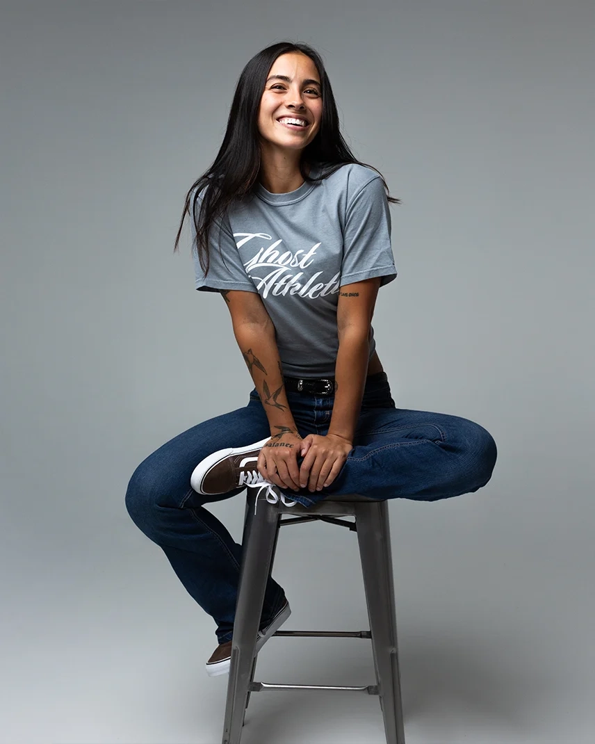 Model on a stool in the GHOST® ATHLETICS tee